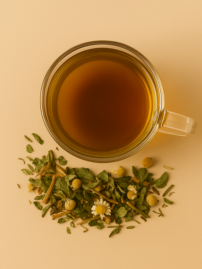Overhead view of a glass mug filled with steeped Glow Tea, surrounded by loose herbal ingredients including chamomile, spearmint, and nettle.